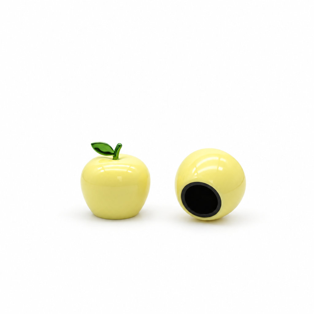 Yellow apple-shaped perfume cap with a green leaf, showing the front view and black-lined opening underneath.