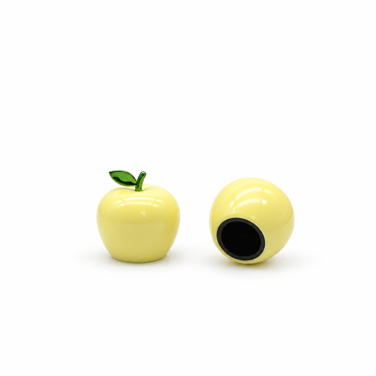 Yellow apple-shaped perfume cap with a green leaf, showing the front view and black-lined opening underneath.