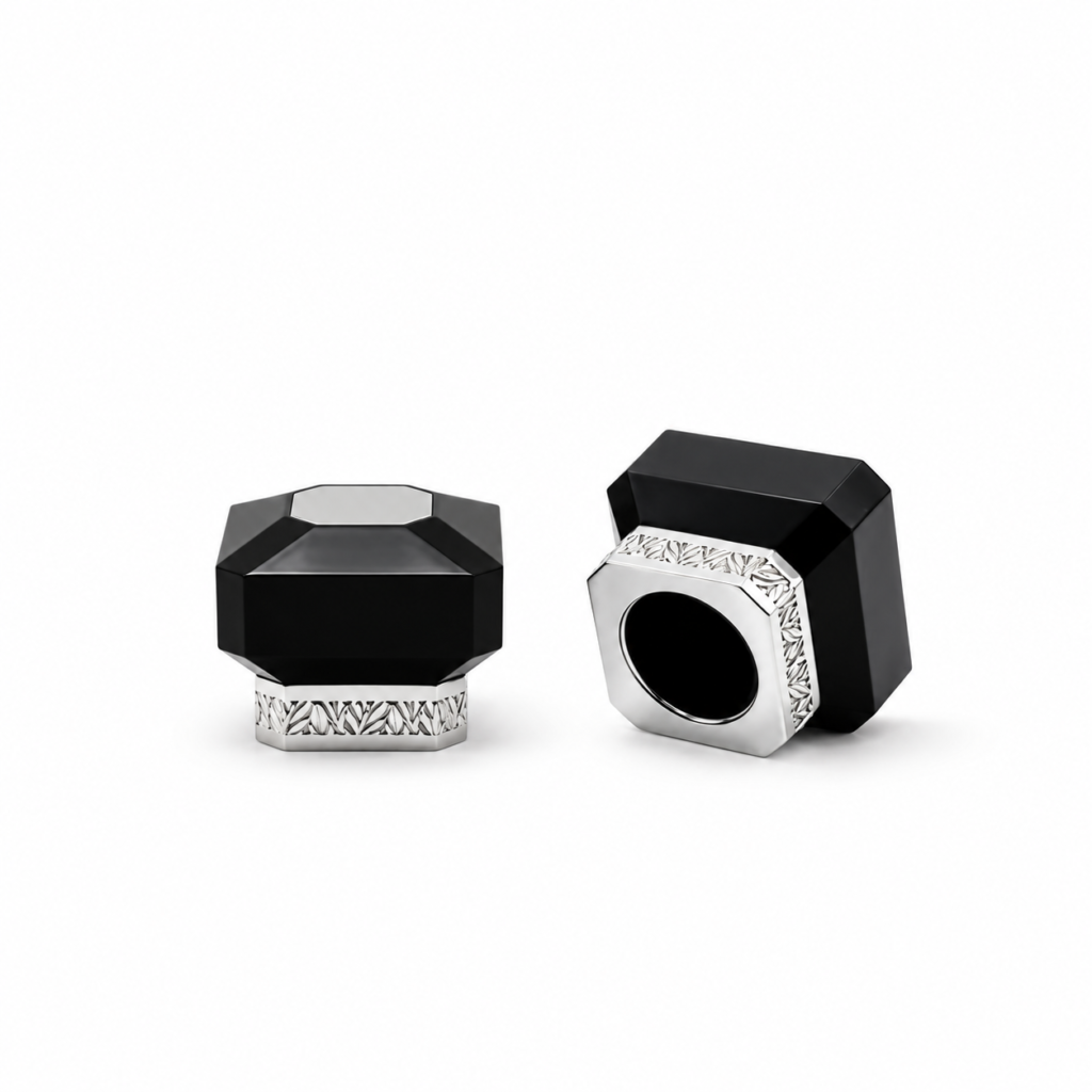 Black faceted perfume bottle cap with a silver top accent and patterned silver base, shown from the front.