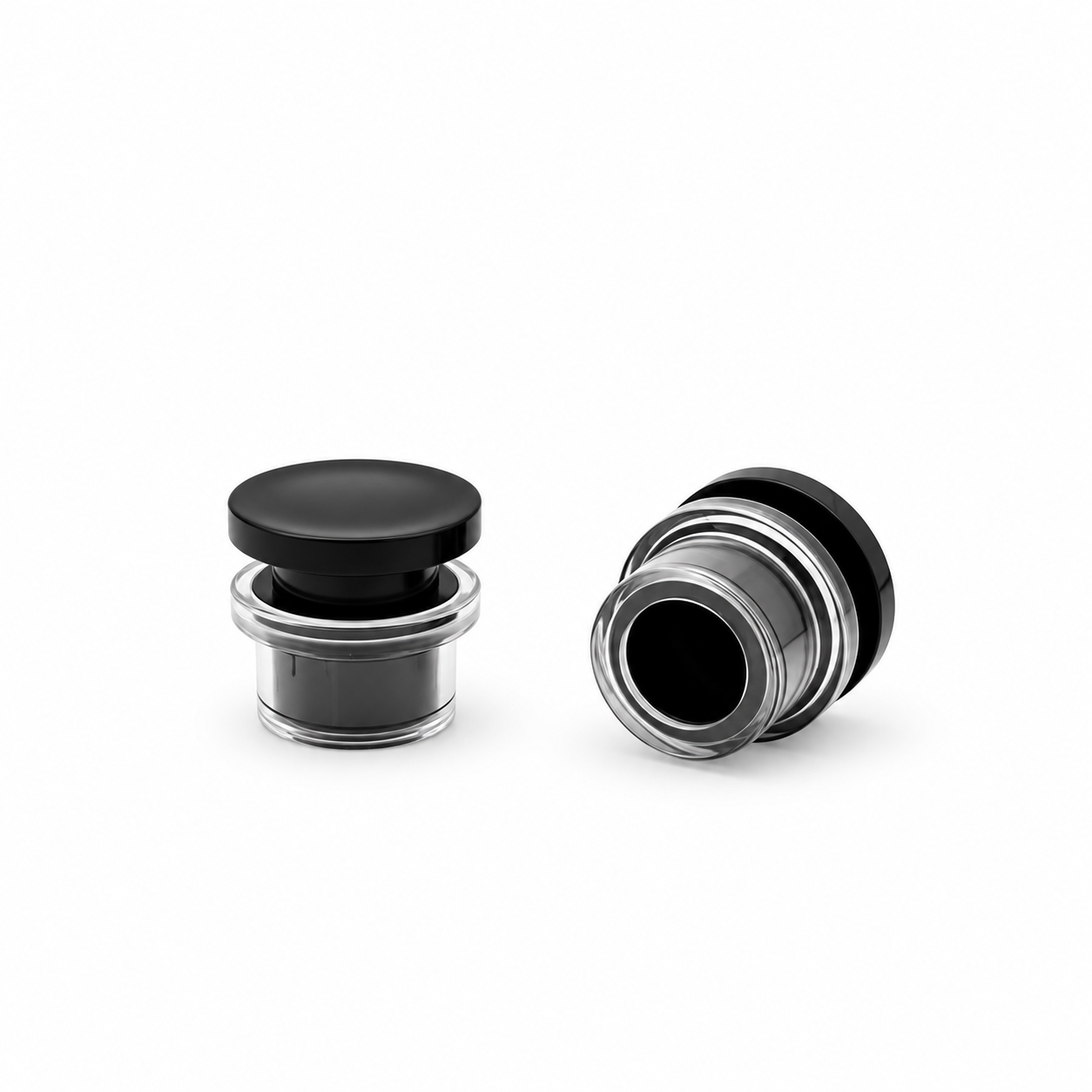 Perfume bottle cap with a black disc top and clear cylindrical outer shell, shown upright and tilted to reveal the bottom opening.