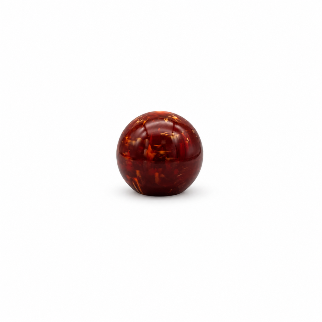 Spherical perfume bottle cap with a smooth, glossy surface and irregular amber marbling.